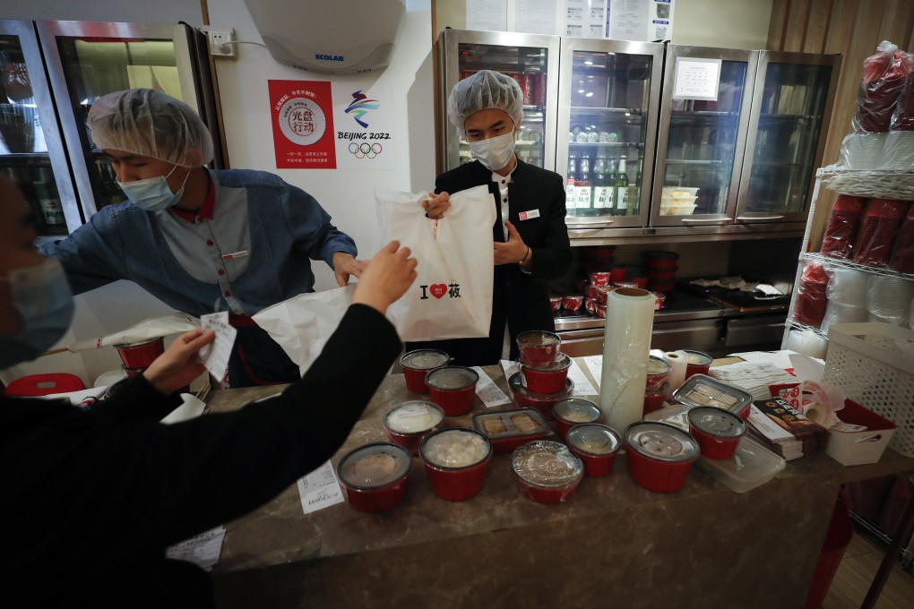 Workers wearing protective face masks and head covers pack food orders for take-out at the Xibei restaurant inside a shopping mall in Beijing, China. Photo: AP
