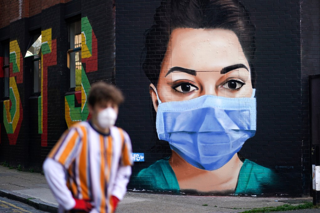 A man walks past a mural depicting a nurse in Shoreditch, London. Photo: Reuters