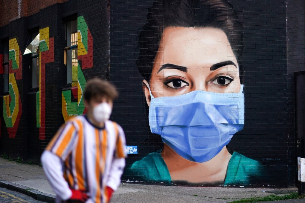 A man walks past a mural depicting a nurse in Shoreditch, London. Photo: Reuters