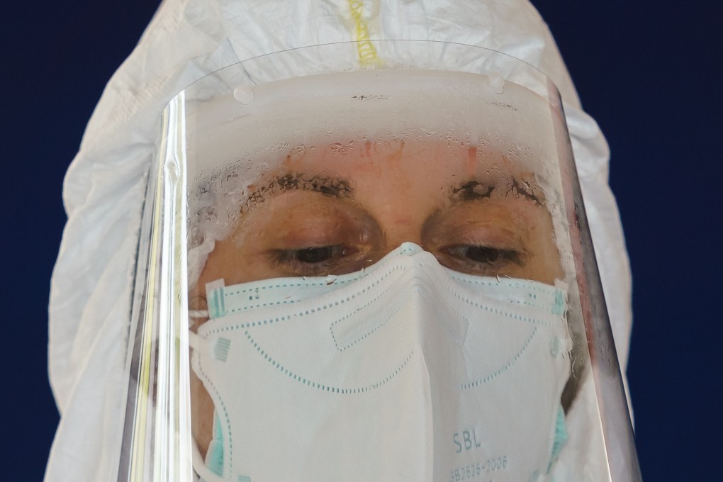A health care worker in protective gear collects samples from drivers at a drive-through testing point in Spain. Photo: AFP