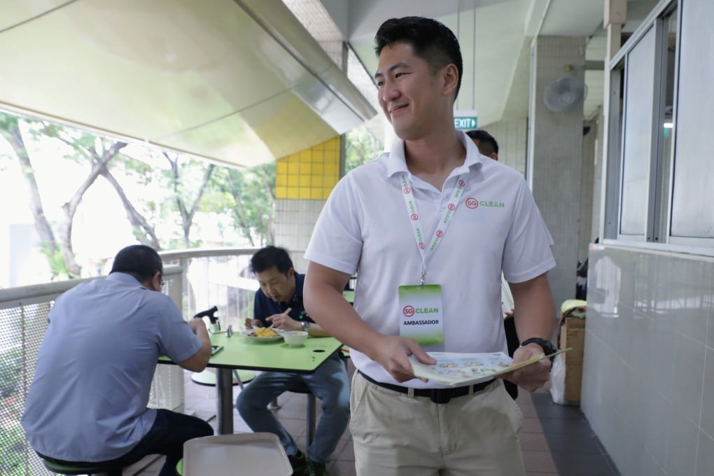 Jonathan Lau, a Jetstar pilot redeployed as a government virus awareness ambassador, speaks to diners at a food centre in Singapore about social distancing, following the outbreak of Covid-19. Photo: Reuters