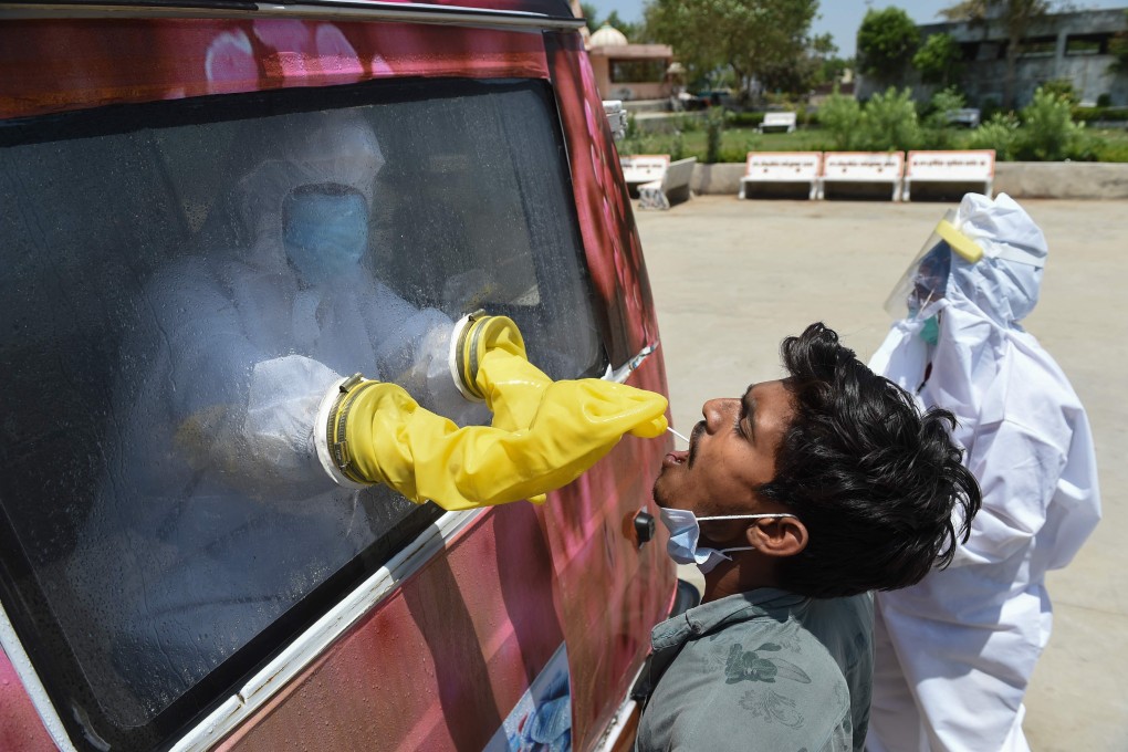 A health official uses a swab to collect a sample from a man for Covid-19 testing from inside a mobile testing van during a government-imposed nationwide lockdown in India. Photo: AFP