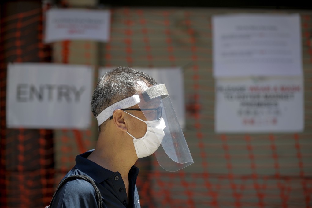 A safe distancing ambassador wearing a surgical mask and face shield outside a market in Singapore. Photo: EPA