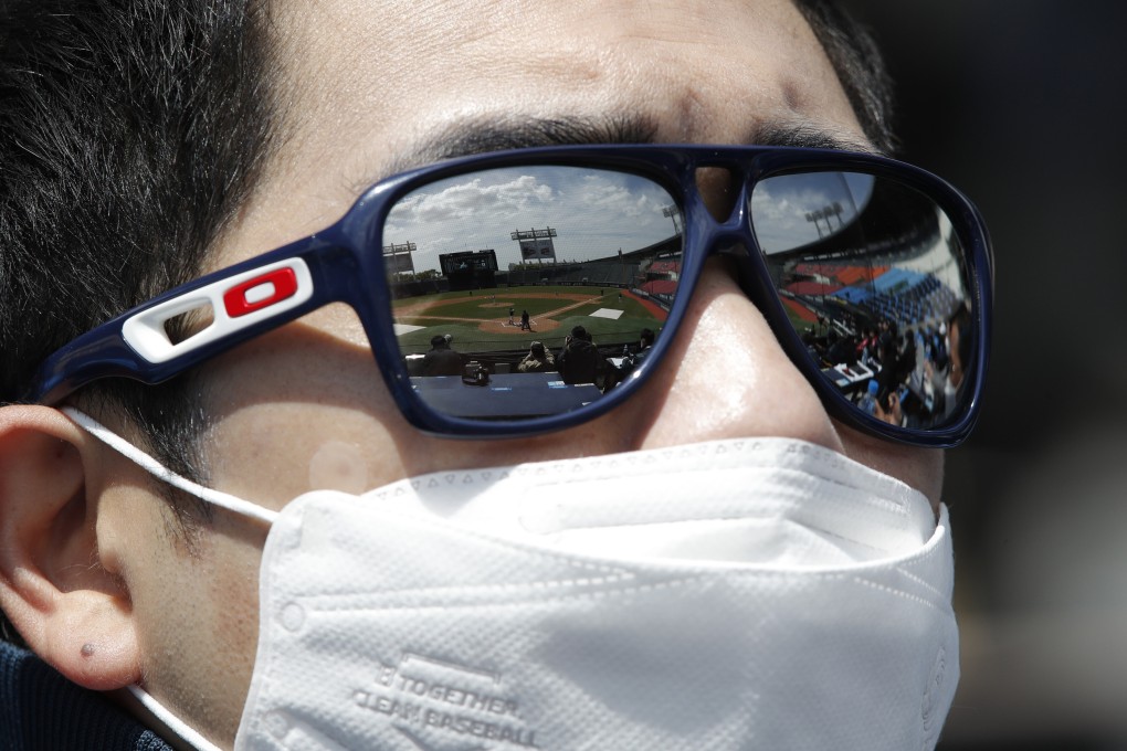 Empty spectator seats are reflected on the sunglasses of a team member wearing a mask as a precaution against the new coronavirus during the pre-season baseball game between Doosan Bears and LG Twins in Seoul, South Korea, Tuesday, April 21, 2020. South Korea's professional baseball league has decided to begin its new season on May 5, initially without fans, following a postponement over the coronavirus. (AP Photo/Lee Jin-man)