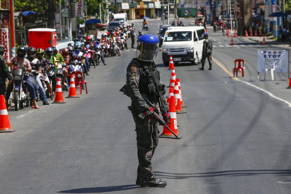 An armed police officer guards a checkpoint in Metro Manila earlier this month amid the antivirus lockdown of Luzon island. Photo: EPA