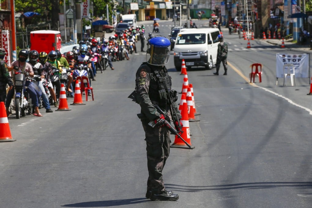 An armed police officer guards a checkpoint in Metro Manila earlier this month amid the antivirus lockdown of Luzon island. Photo: EPA