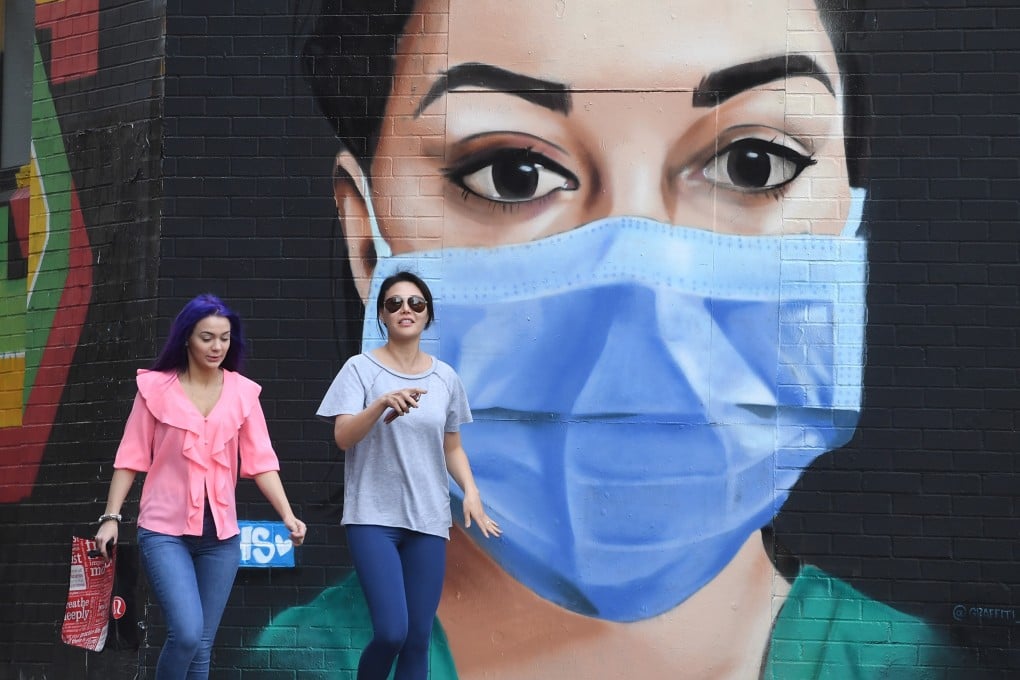 Pedestrians walk past an artwork depicting a nurse wearing a face mask in East London. Photo: EPA