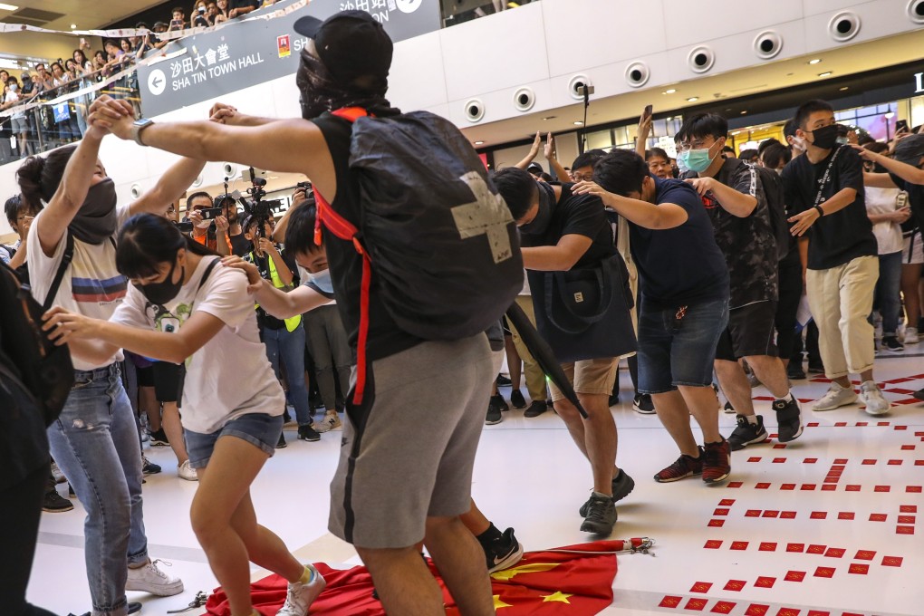 Protesters walk over the national flag during an anti-government protest at New Town Plaza in Sha Tin on September 22, 2019. Photo: Nora Tam