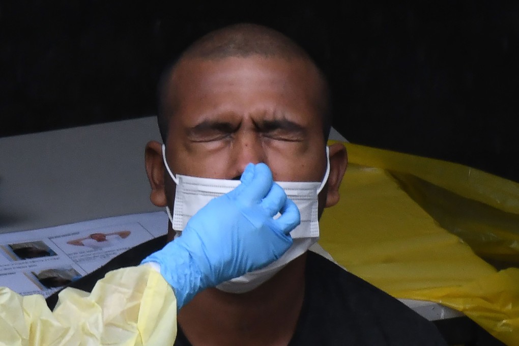 A healthcare worker collects a nasal swab sample from a migrant worker in Singapore. Photo: AFP