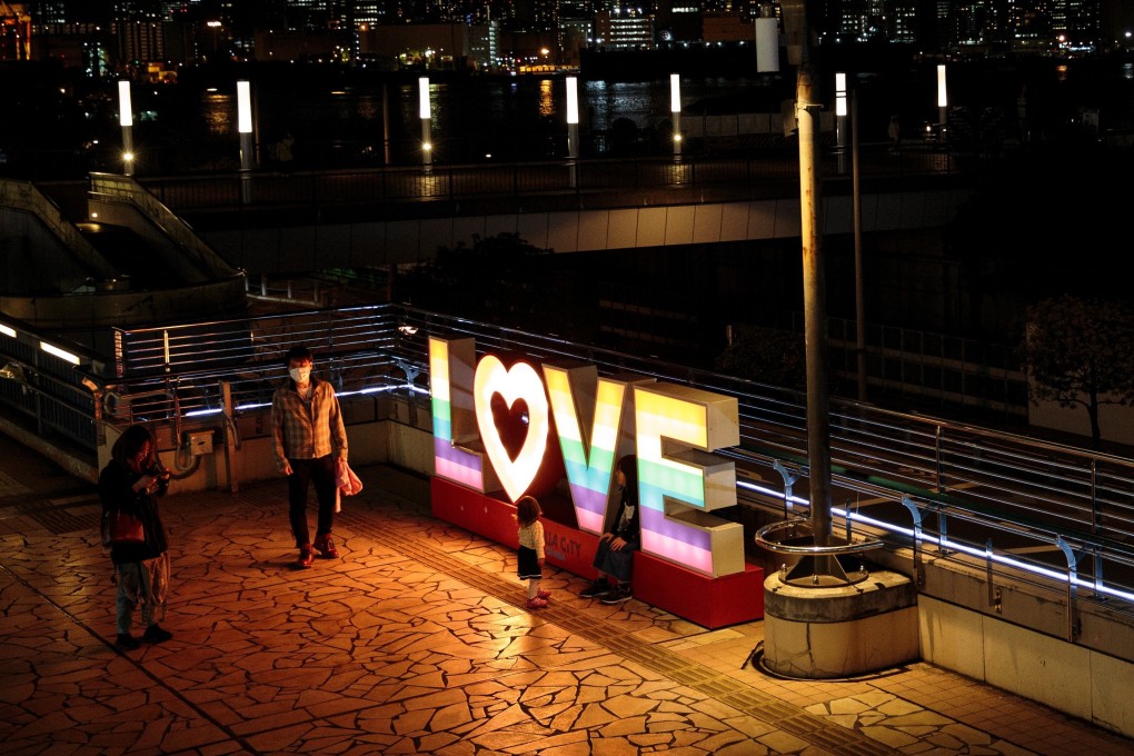 A family stands next to a sign in Tokyo on March 23. Anyone can get sick but everyone can be kinder. Photo: AFP