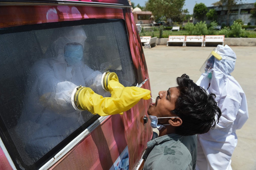 A mobile Covid-19 testing van in India takes a sample from a man during the lockdown. Photo: AFP