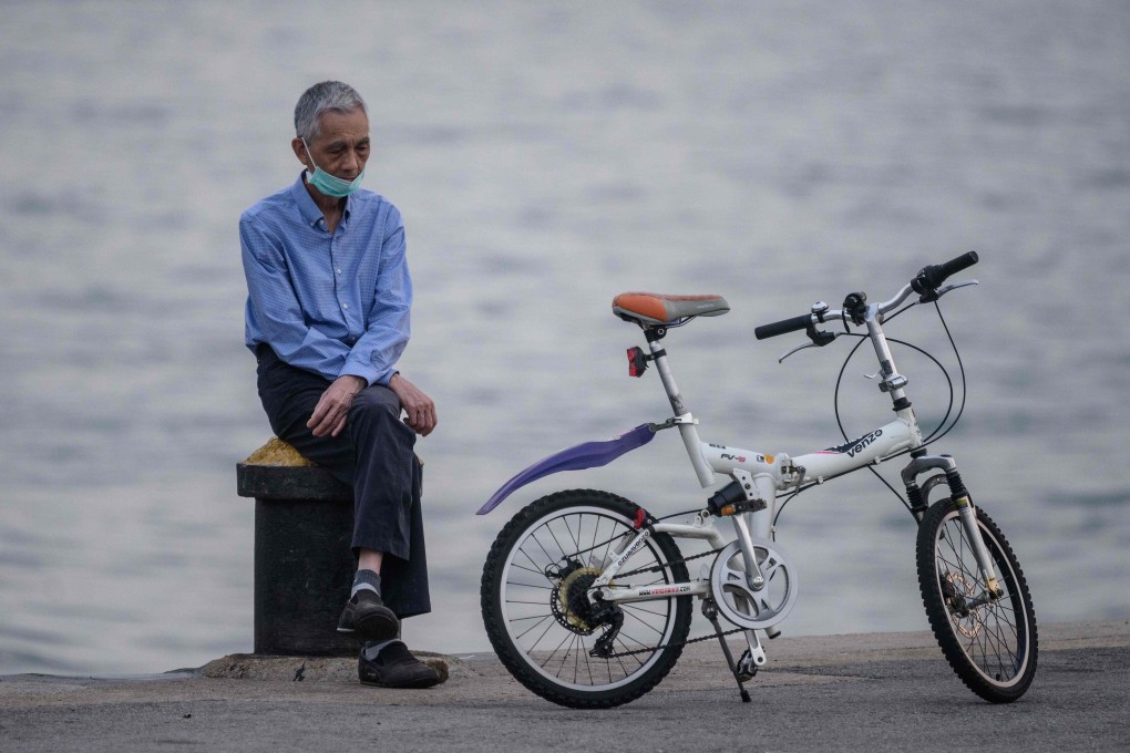 A man wears a face mask, as a precautionary measure against the coronavirus, as he rests next to his bicycle while sitting on a mooring on a cargo dock in Hong Kong. Photo: AFP