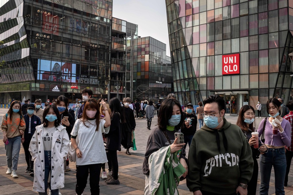 People wearing face masks amid concerns over the coronavirus walk past a shopping centre in Beijing. Governments around the world are unleashing trillions of dollars to keep businesses and workers afloat. Photo: AFP