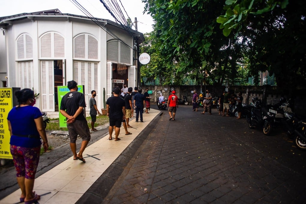 Residents of Bali, whose livelihoods have been threatened by the pandemic’s impact on the island’s tourism industry, line up to collect food and sanitary essentials from Project Nasi, a charitable organisation set up by Australian expats. Photo: Project Nasi