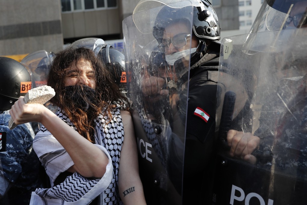 An anti-government protester confronts police with a stone during a protest in Beirut, Lebanon. Photo: AP