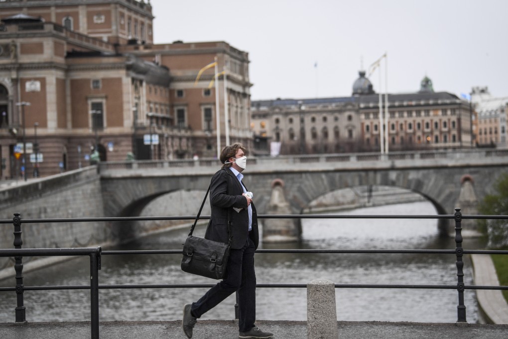 A man wearing a protective mask walks in the rain past the Royal Swedish Opera in Stockholm, Sweden on Monday. Photo: EPA-EFE