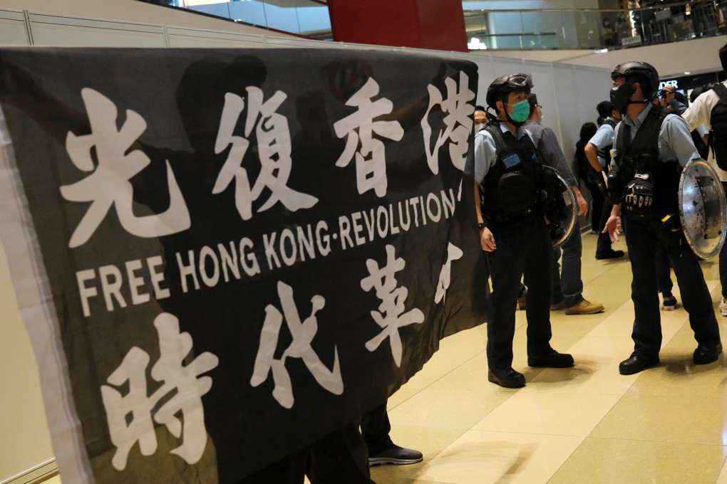 An anti-government protester holds a flag next to riot police at a rally in April, 2020. Photo: Reuters