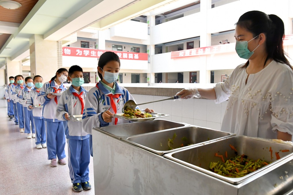 Pupils wait in line to get their meals at Shaanxi Normal University Jinyuan Primary School in Xian, Shaanxi province, on Monday, when students in grades 4-6 returned to school. Photo: Xinhua