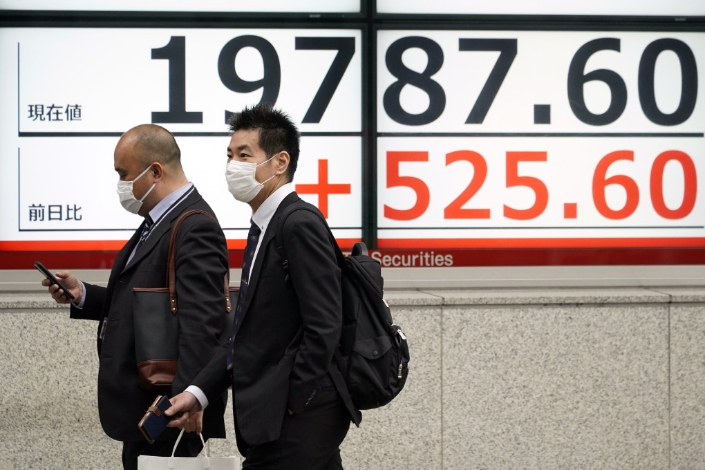 People walk past a stock market indicator board in Tokyo on April 27. Tokyo stocks rose sharply after the Bank of Japan unveiled new stimulus measures to counter the impact of the coronavirus pandemic. Photo: EPA-EFE
