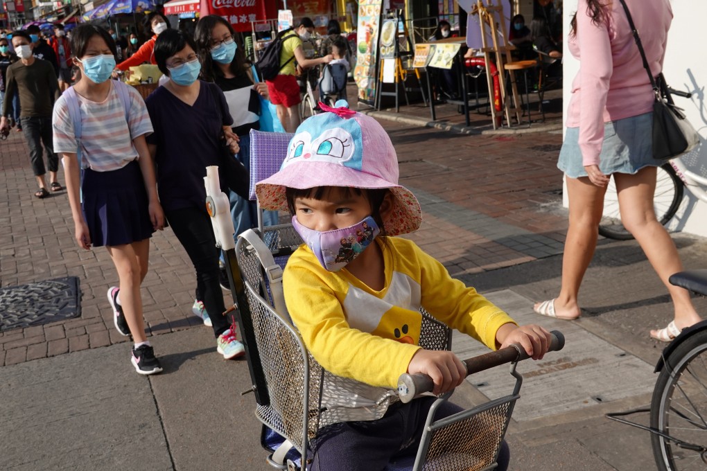 A child wearing a face mask sits on the back seat of a bicycle on Cheung Chau island on April 12, over the Easter weekend. There’s no word on when Hong Kong’s primary school pupils might return to class. Photo: Reuters