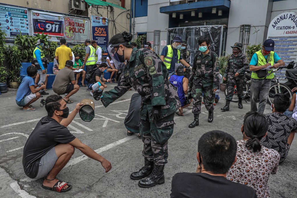 Members of the public, detained for roaming the streets without relevant passes amid the Covid-19 pandemic, are processed outside a police station in Manila, the Philippines. Photo: AFP