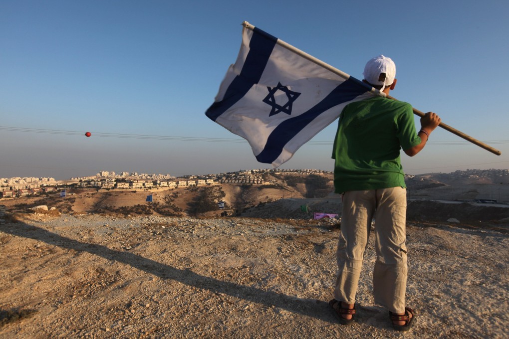 A right-wing supporter holds his national flag near the Jewish settlement of Maale Adumim, east of Jerusalem. File photo: AFP