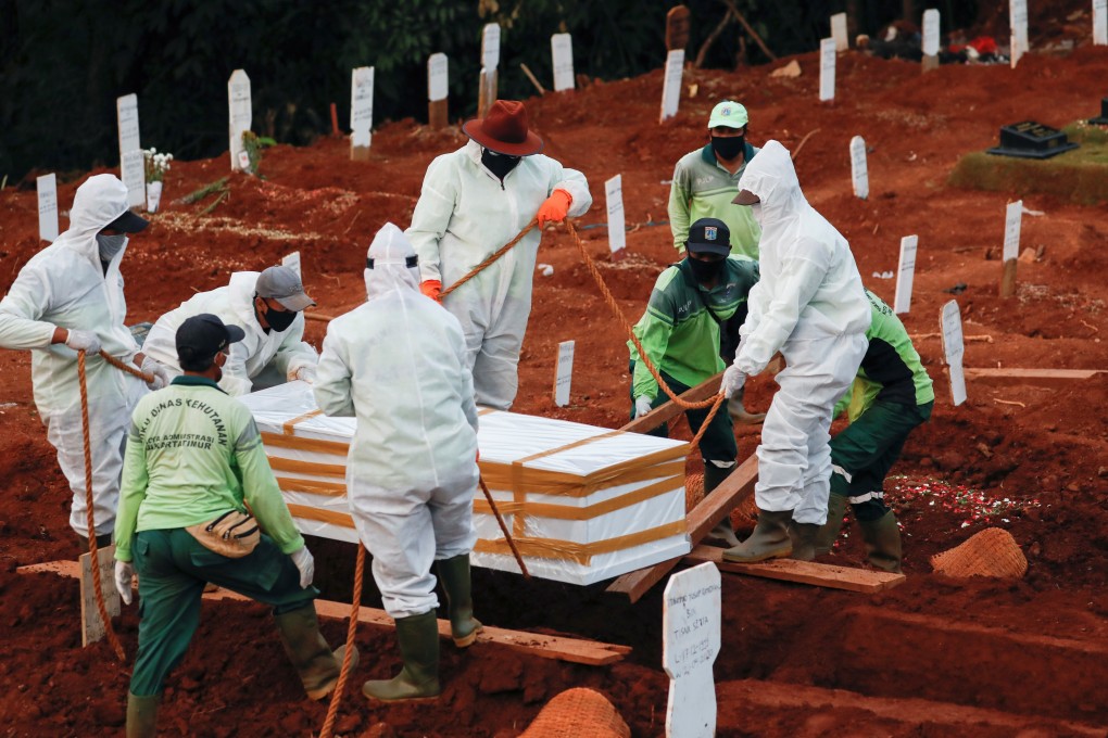 Municipal workers bury a victim of Covid-19. Many villagers in Indonesia are rejecting such burials, reportedly out of fear and ignorance, leading some farmers to offer their land for burials. Photo: Reuters