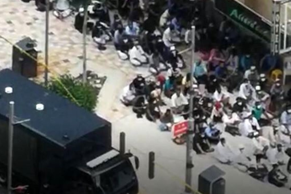 Hundreds of people, most thought to be migrant workers, are lined up outside one of the raided buildings. Photo: Handout