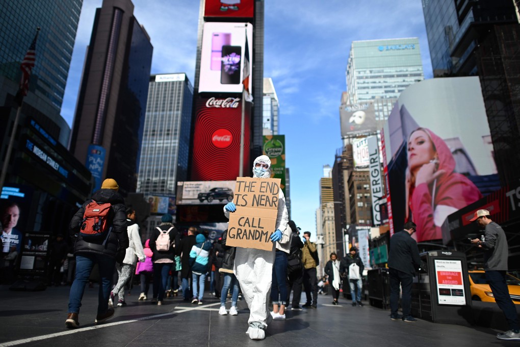 A man wearing a hazmat suit and a mask holds a sign reading “The end is near – call grandma” at Times Square in New York on March 14. Photo: AFP