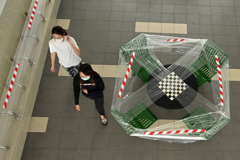 People, wearing face masks, walk past public benches that have been cordoned off in Singapore. Photo: AFP