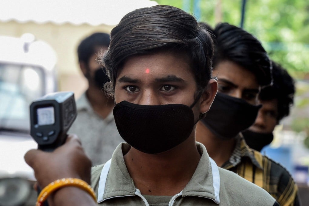 A government official checks the temperature of migrant workers to prepare a list of those staying in a camp in New Delhi during India’s virus lockdown. Photo: AFP