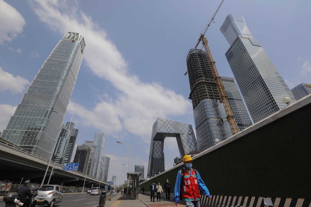 A migrant worker wearing a face mask walks around the central business district of Beijing. Photo: EPA-EFE