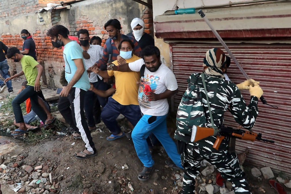 Security officers enforce distancing while people queue up outside a liquor shop in New Delhi, India. Photo: EPA