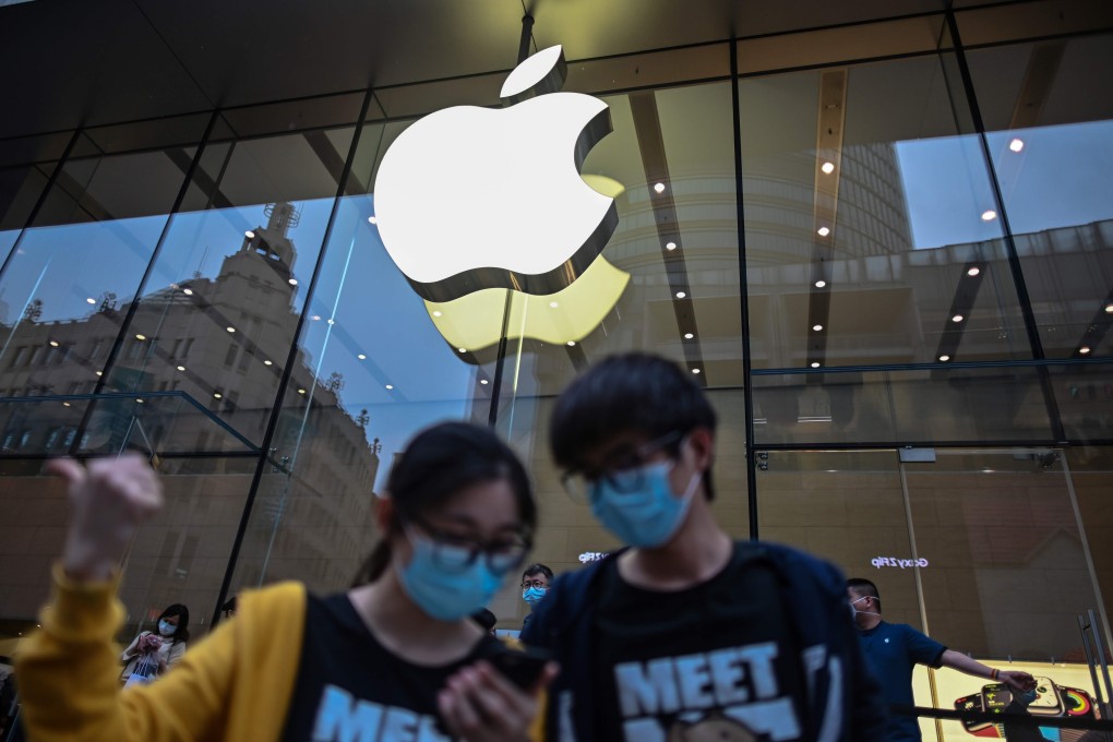 People wearing face masks look at a cellphone outside an Apple store during a May Day holiday in Shanghai on May 1, 2020. Photo: AFP