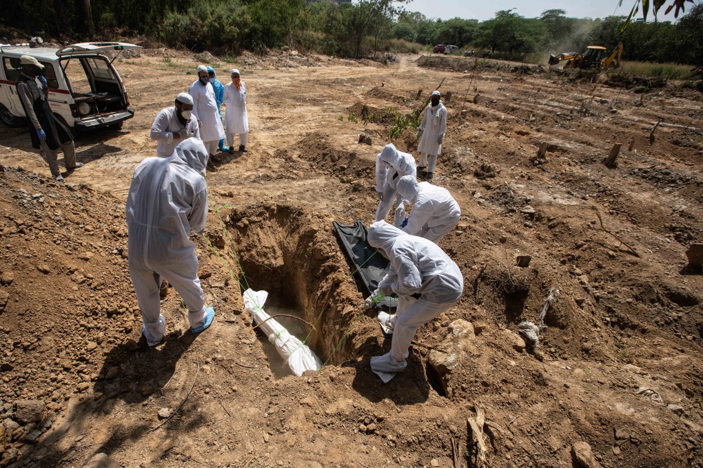 Relatives and health care workers in protective suits bury the body of a man who died from Covid-19 in a graveyard in India. Photo: DPA