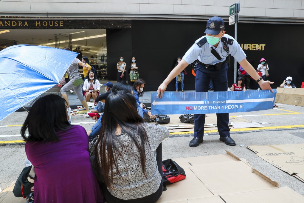 A police officer tries to disperse the migrant domestic workers gathered on their day off in Hong Kong’s Central district on April 26, in an effort to enforce social distancing measures the city government put in place to battle the Covid-19 outbreak. Photo: Edmond So