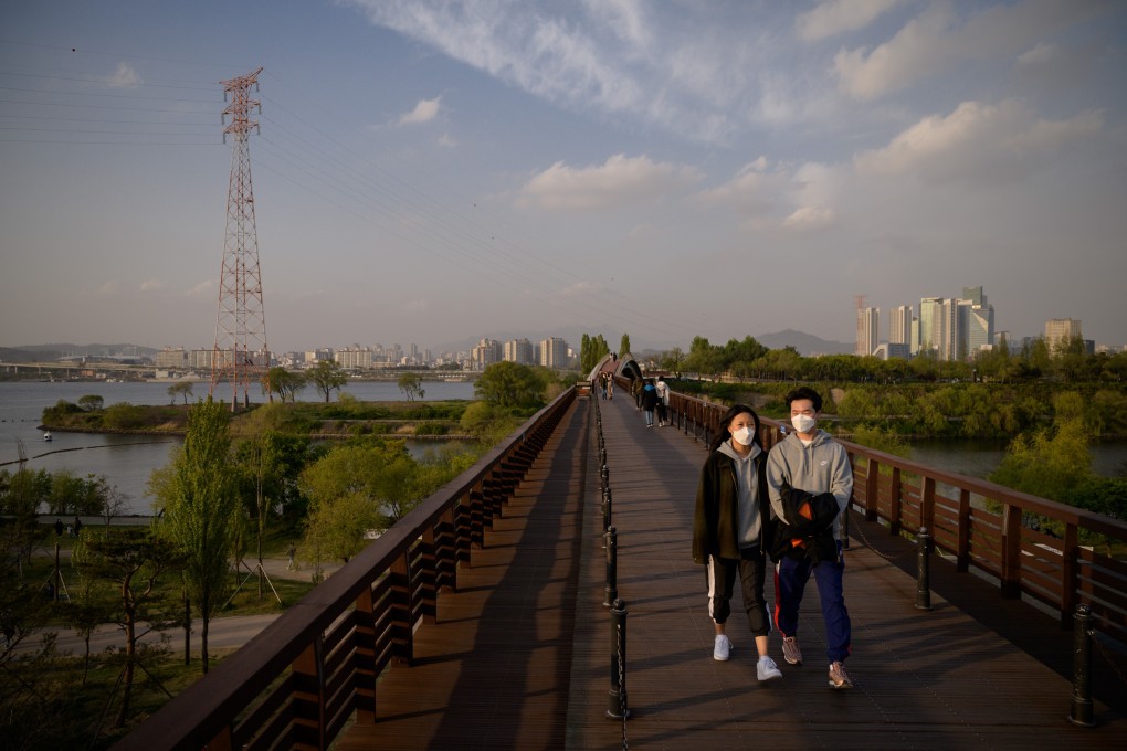 People wearing face masks are seen walking on a bridge, with the Han river and Seoul’s skyline in the background. South Korea’s ‘New Deal’ aims to boost the country’s economic growth potential and create sustainable jobs for future generations. Photo: Agence France-Presse