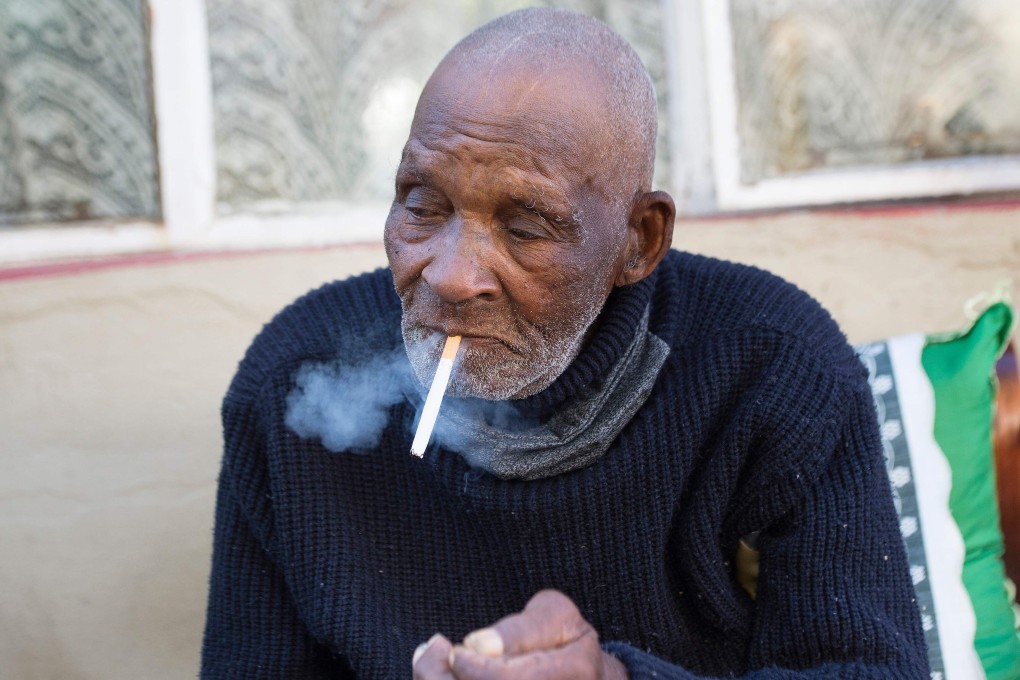 Fredie Blom enjoys a cigarette as he celebrates his 116th birthday at his home in Delft, near Cape Town. Photo: AFP