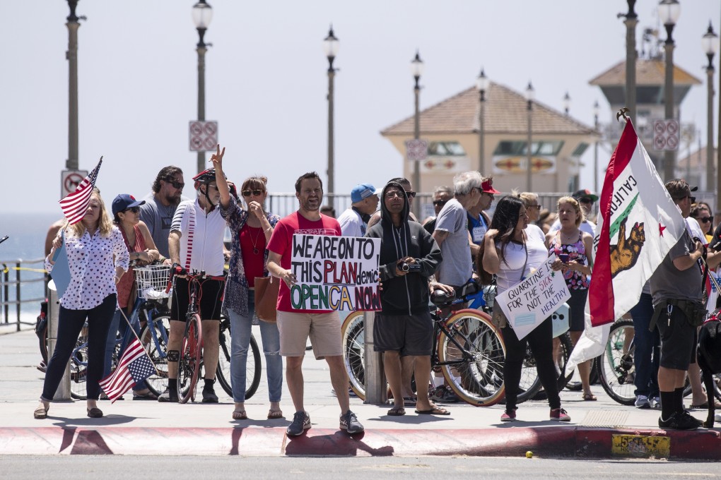 A protester holds a poster reading 'We are onto this plandemic open CA now' during a small demonstration in California. Photo: EPA