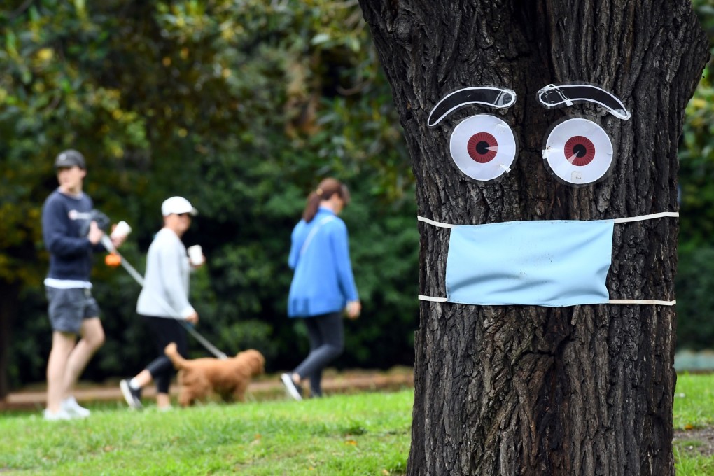 People walk past a mask and eyes stapled to a tree in Melbourne on April 20. While governments are being faulted for not preparing adequately for a pandemic, despite warnings, the climate change crisis is hiding in plain sight. Photo: AFP