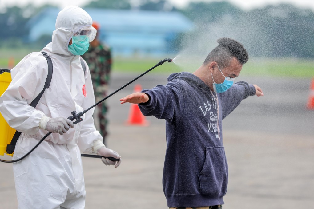 An Indonesian migrant worker gets sprayed with disinfectant upon arrival in Medan, North Sumatra. Photo: EPA-EFE