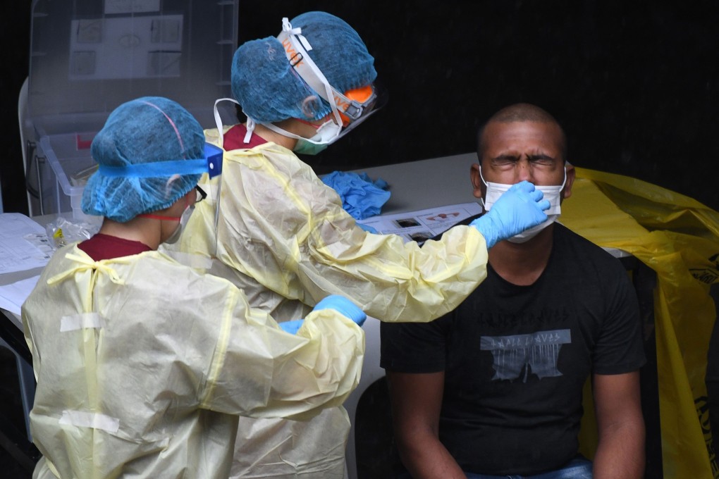 Singaporean health care workers collect a nasal swab sample from a migrant worker for Covid-19 testing. Photo: AFP