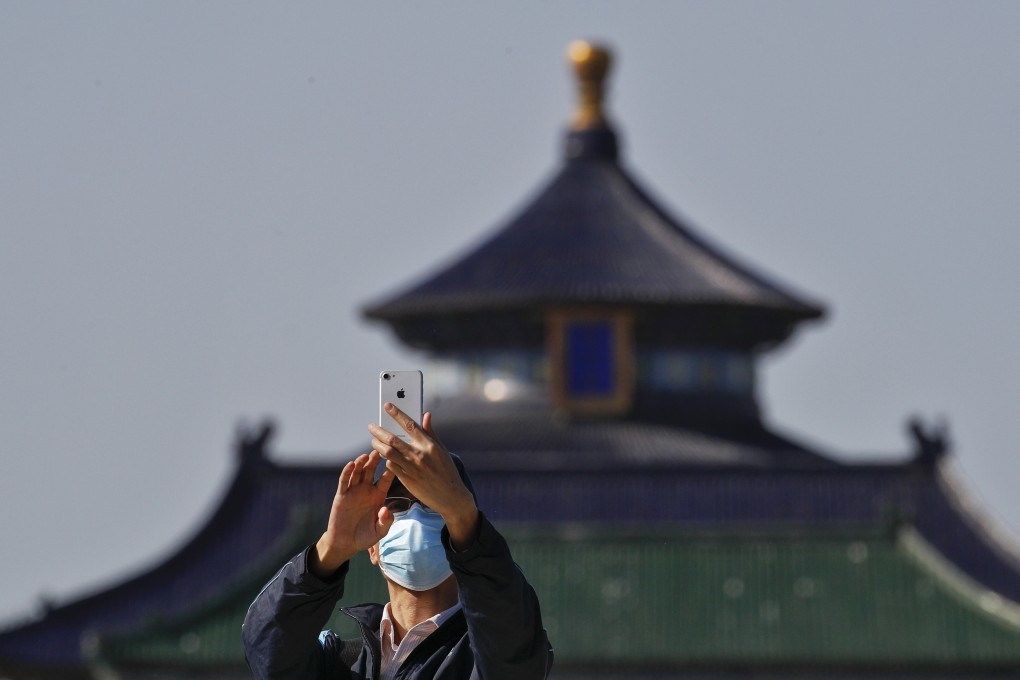 A man wearing a protective face mask uses his smartphone to take a photo at the Temple of Heaven in Beijing on May 10. China’s strong smartphone shipments in April suggest a rebound in the domestic market. Photo: AP