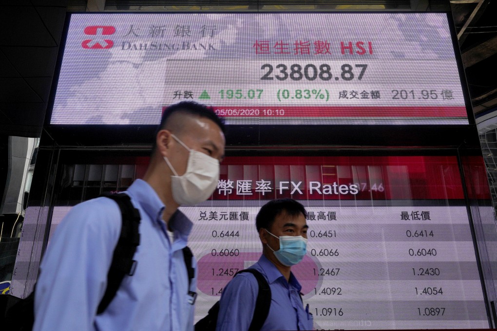 People wearing face masks walk past a bank electronic board showing the Hong Kong share index on May 5, 2020. Photo: Associated Press