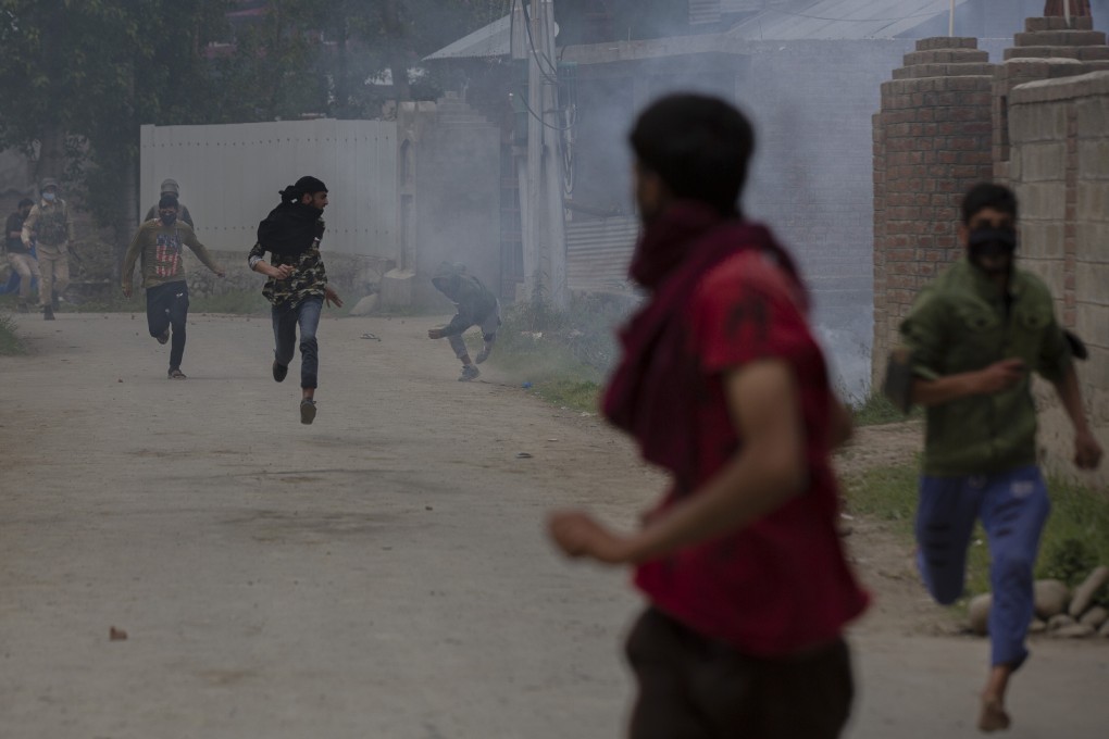 Kashmiri villagers run for cover as policemen chase after firing tear gas during a protest on May 13, 2020. Photo: AP