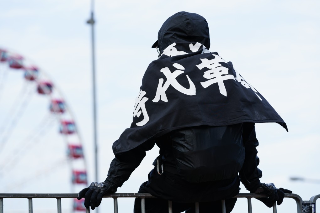 A masked protester wearing a pro-democracy flag sits on a railing during a rally in Central, Hong Kong, on January 12. Photo: Shutterstock