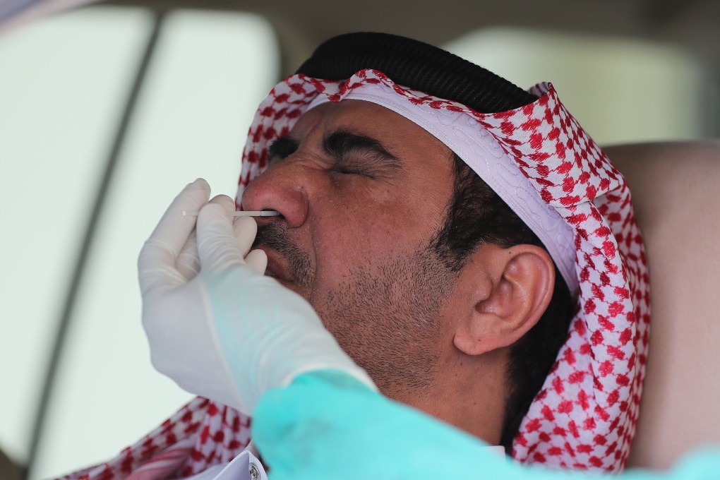 A health worker collects a swab sample from a man at a drive-through testing service for coronavirus in the Qatari capital Doha. Photo: AFP
