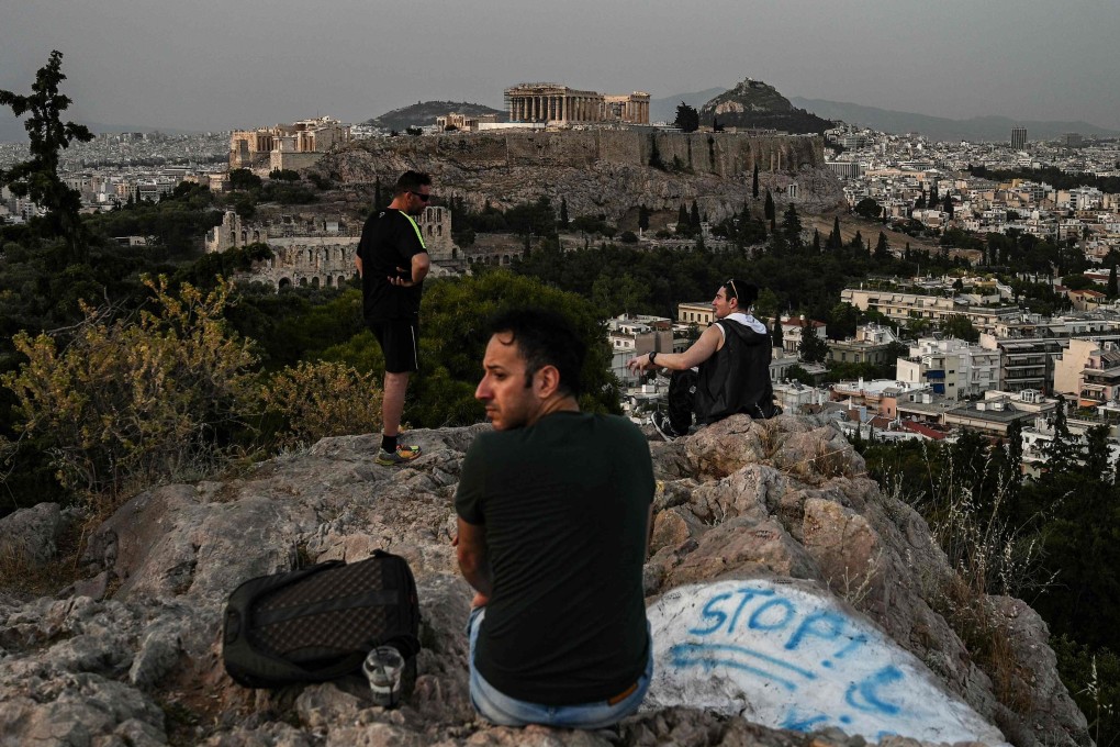 Visitors on a hill facing the ancient Temple of Parthenon atop the Acropolis hill in Athens. Photo: AFP