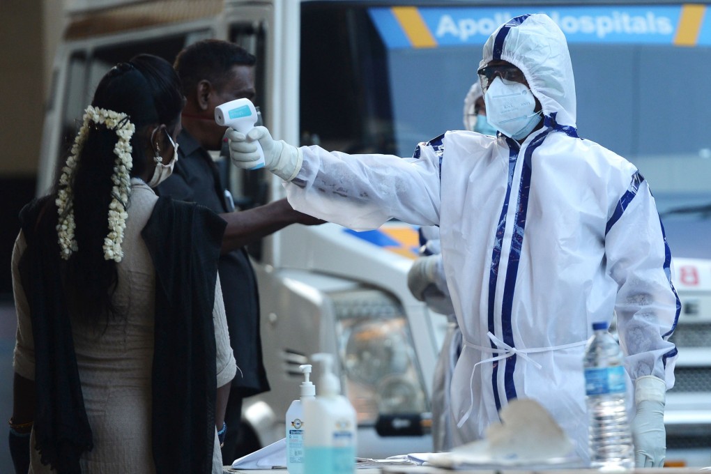 A health official checks the body temperatures of passengers in Chennai. Photo: AFP