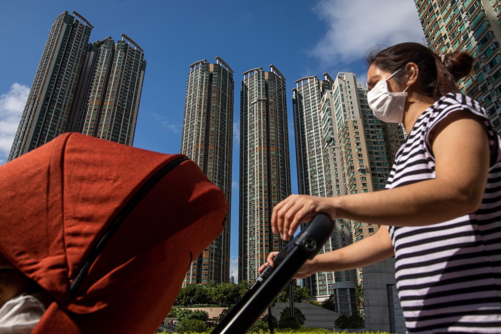 A person wearing a protective mask pushes a stroller past residential buildings near the West Kowloon station in Hong Kong. Photo: Bloomberg